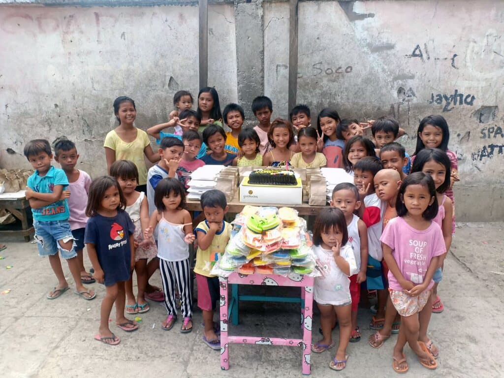 A monthly birthday party: the whole group around a table with a cake and gift bags.