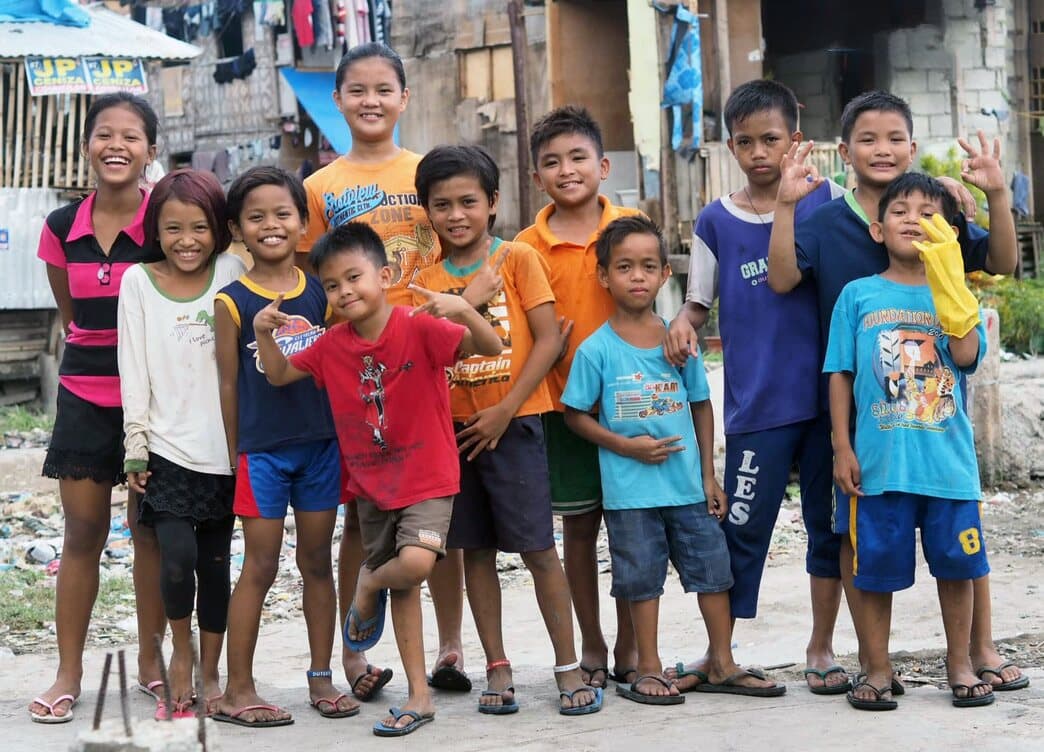 Kids in work gloves after a clean-up drive, posing proudly in the street.