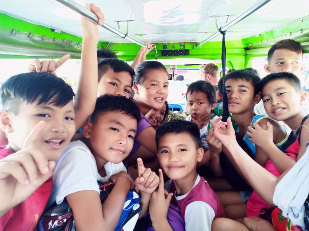 Boys packed into a jeepney on the way to an outing, pulling faces at the camera.