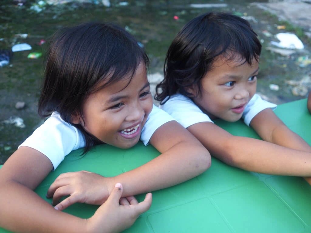 Two small girls from the Hay Nako Juniors leaning on a green table, laughing.