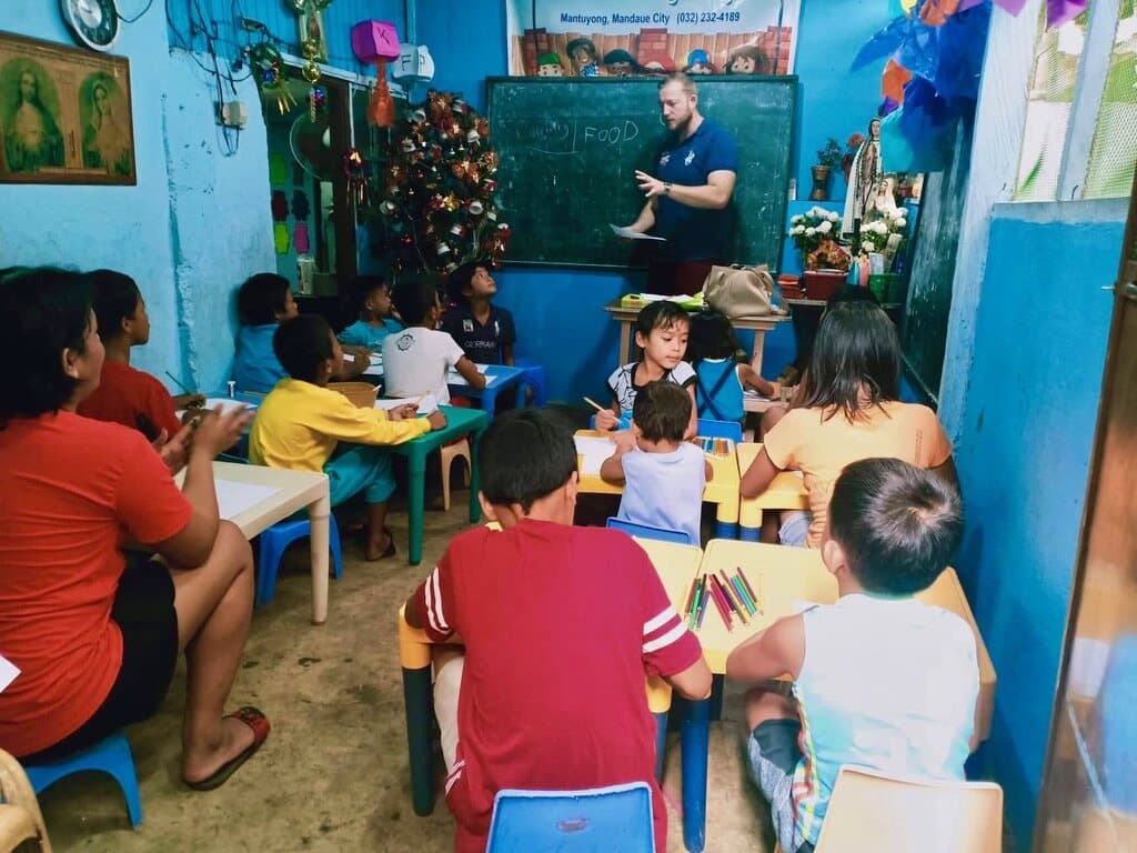 The one rented room: children at small tables drawing, and a teacher at the blackboard.