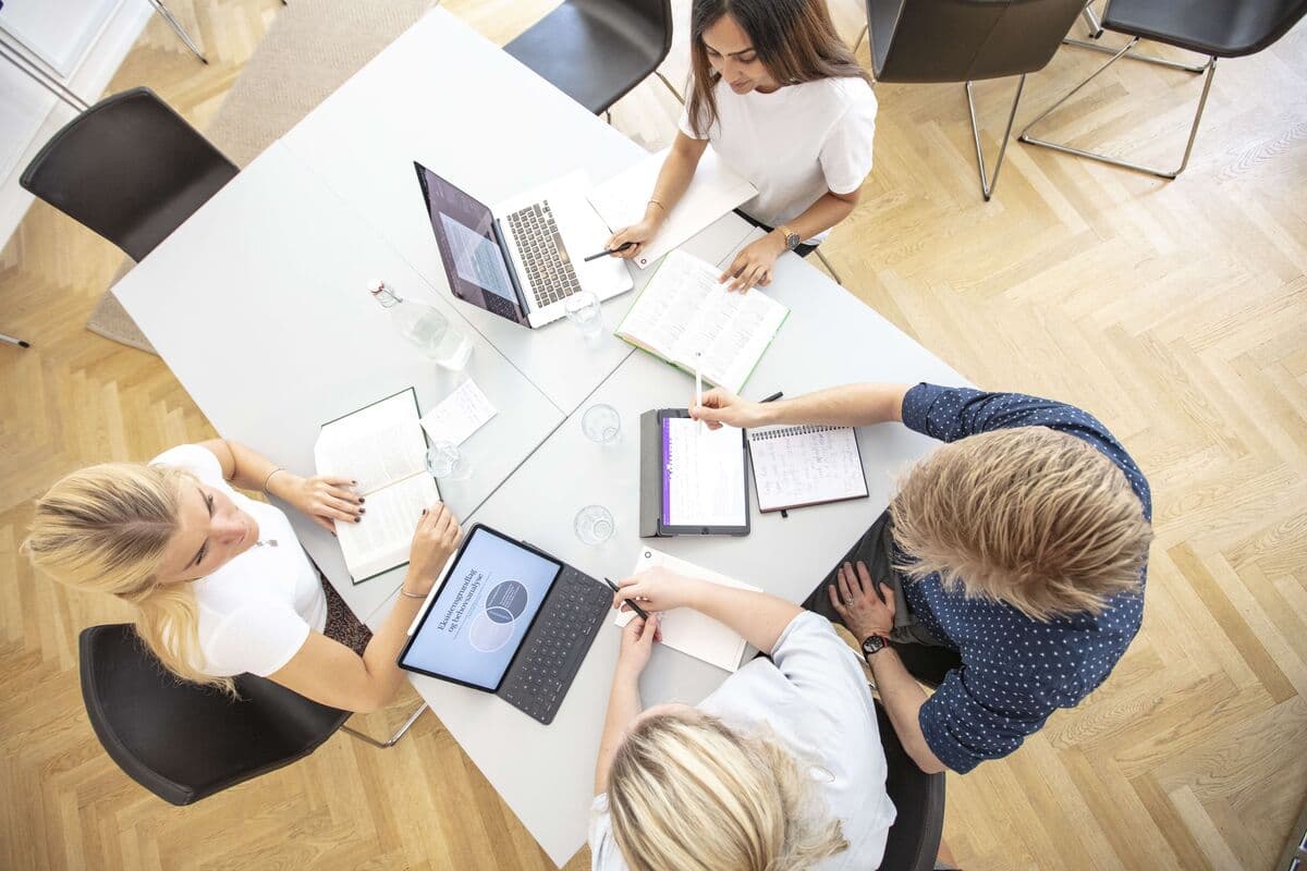 A study group seen from above: laptops, notebooks and a tablet on the table.